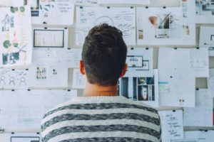 man looking at a wall with pieces of paper