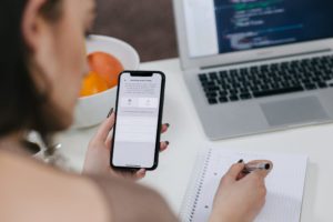 Woman holding a cell phone and taking notes